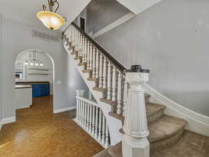 Stairway with tile patterned flooring and arched walkways