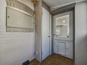 Bathroom featuring brick wall, vanity, and dark tile patterned floors