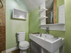 Full bathroom featuring a tile shower, vanity, and a textured ceiling