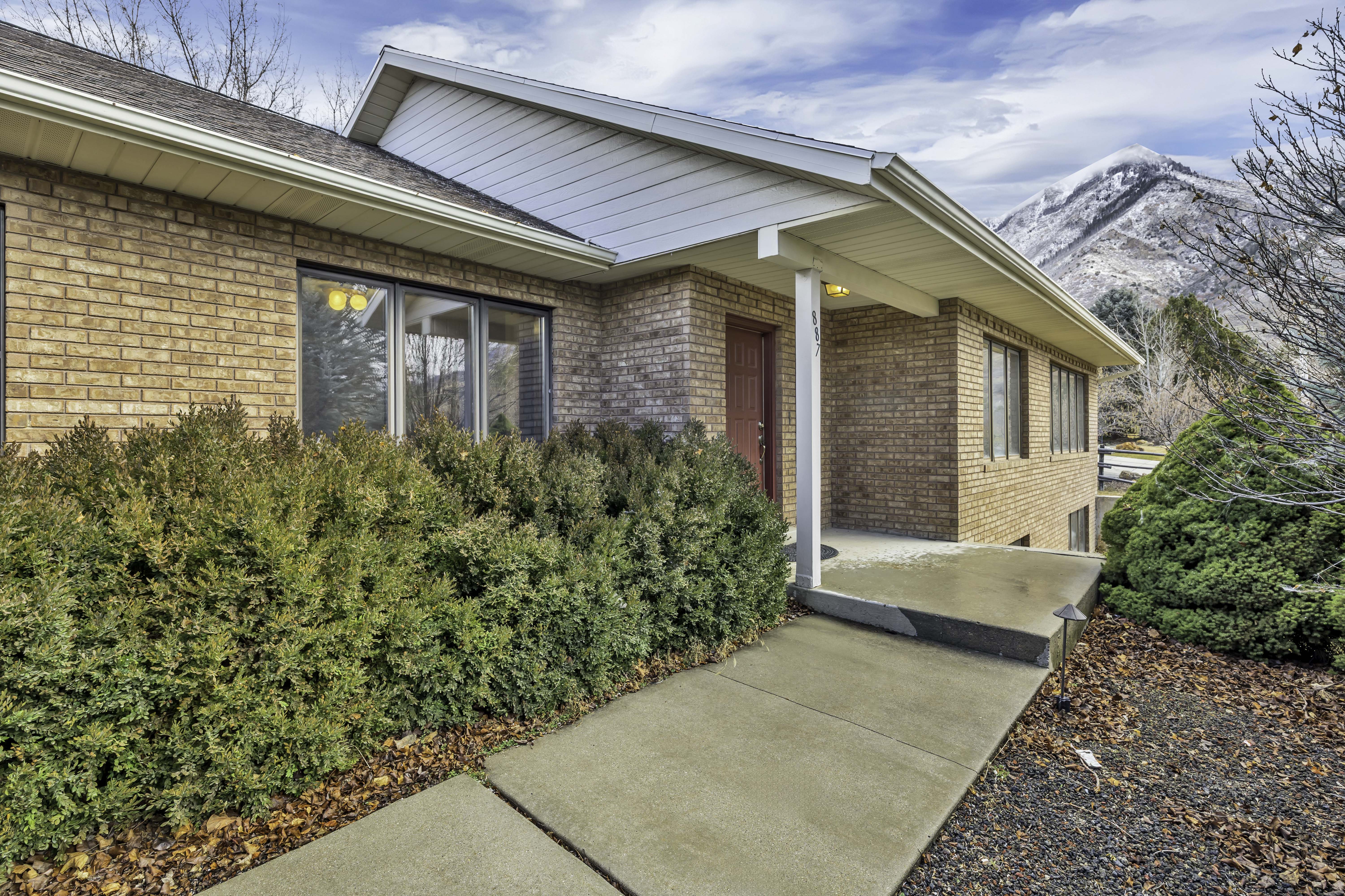 View of exterior entry with covered porch, brick siding, and a mountain view
