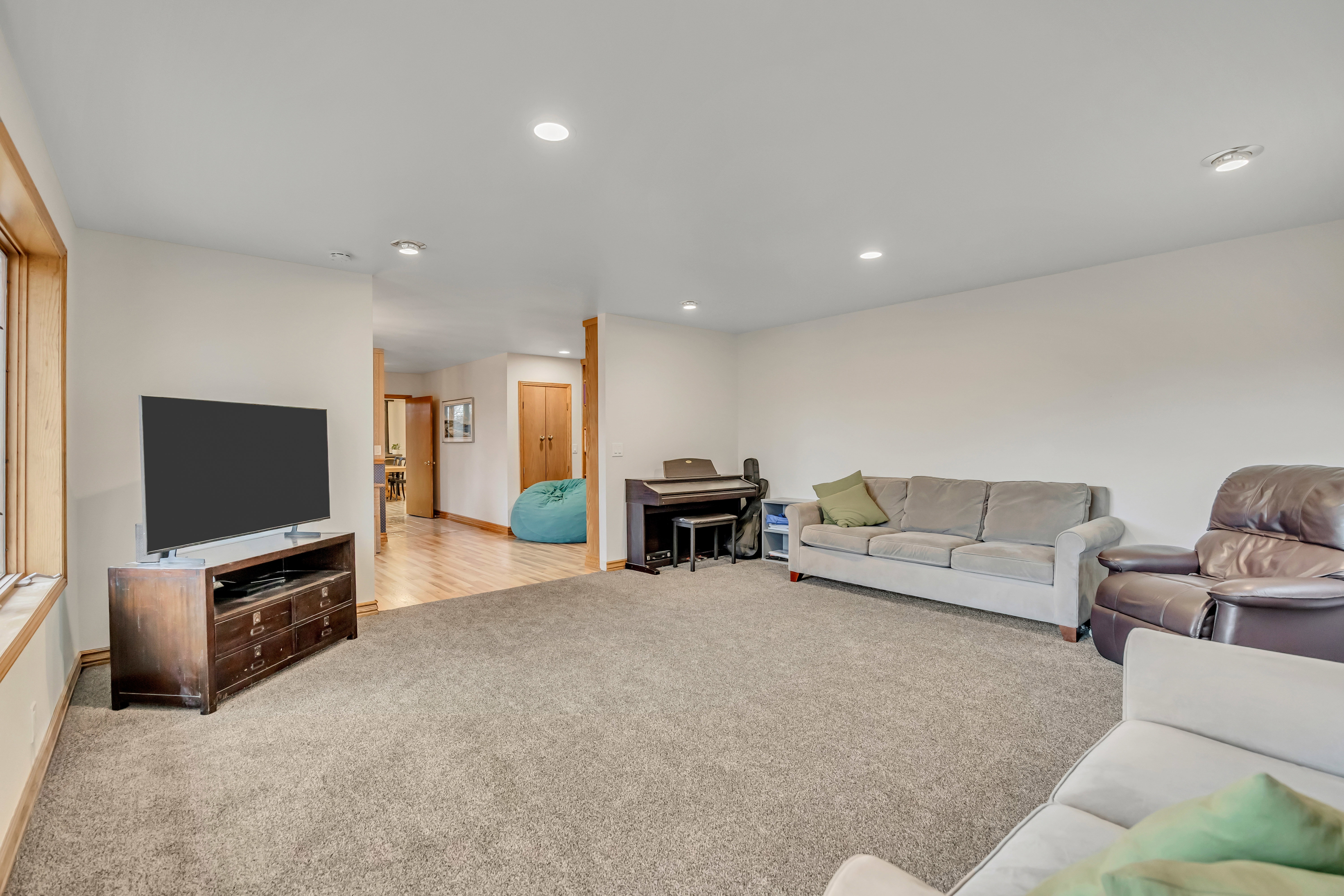 Living area with light carpet and recessed lighting