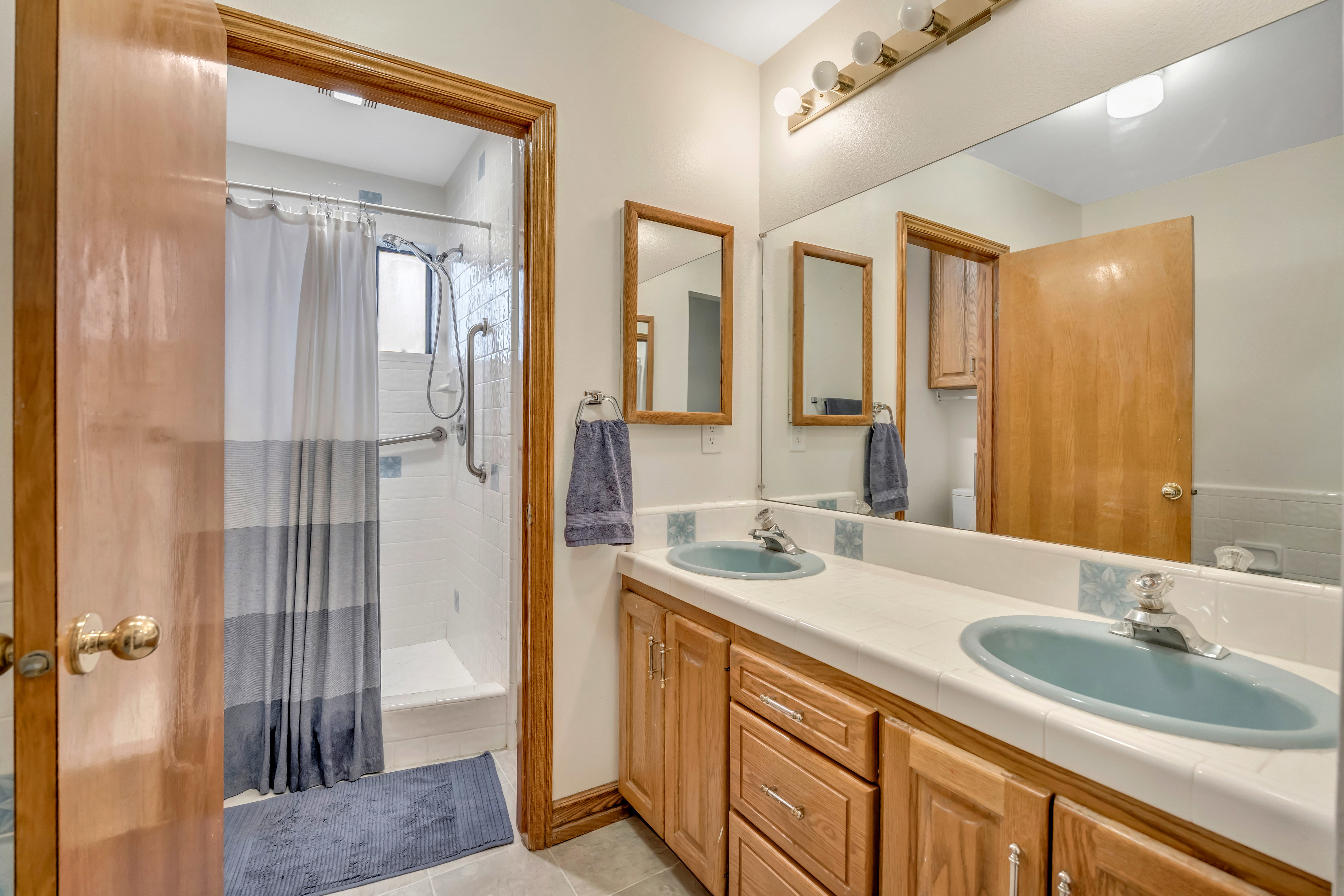 Bathroom with double vanity, a shower stall, and light tile patterned floors