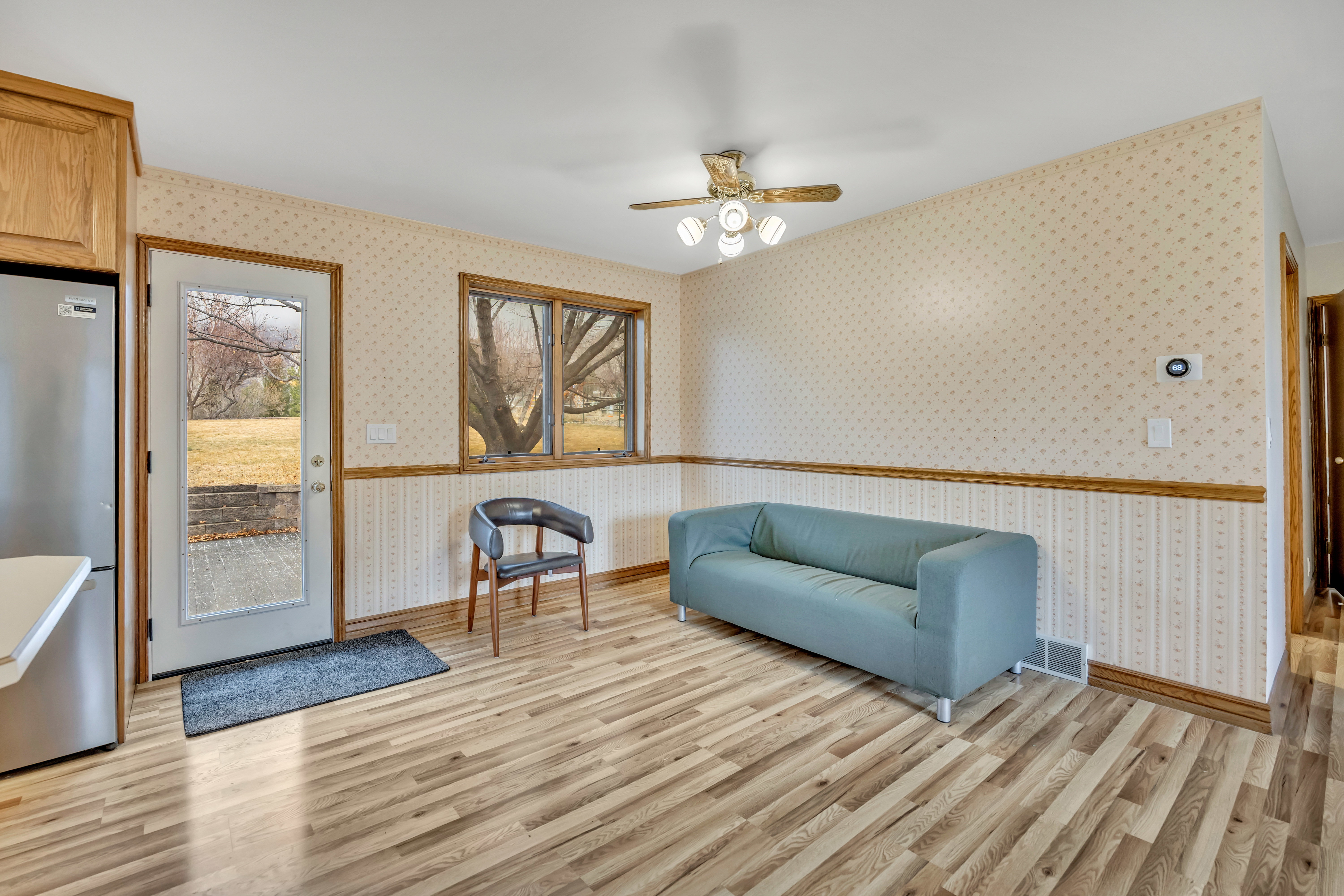 Living area with a ceiling fan, light wood finished floors, and wallpapered walls