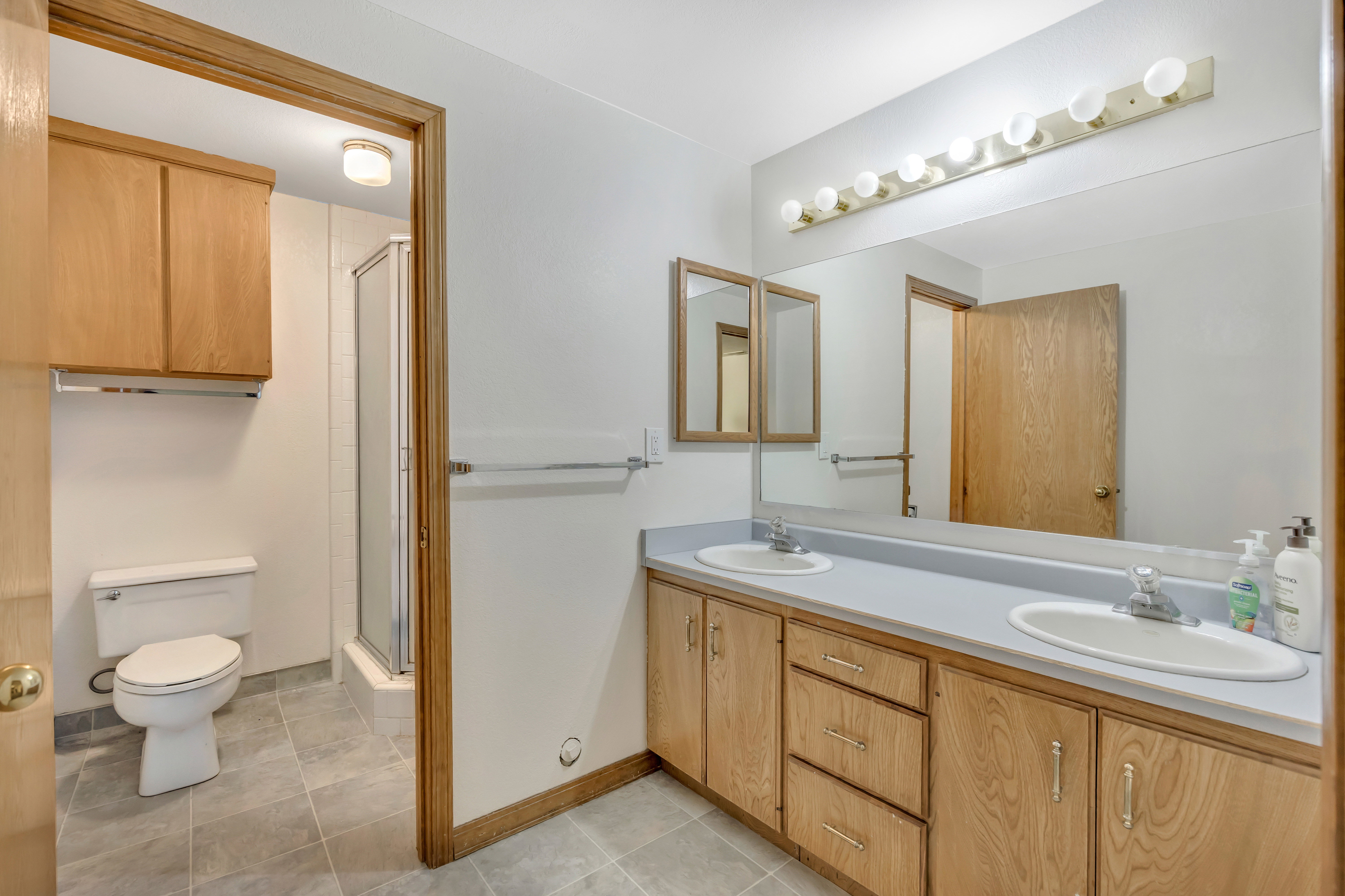 Full bath featuring double vanity, a stall shower, and light tile patterned flooring