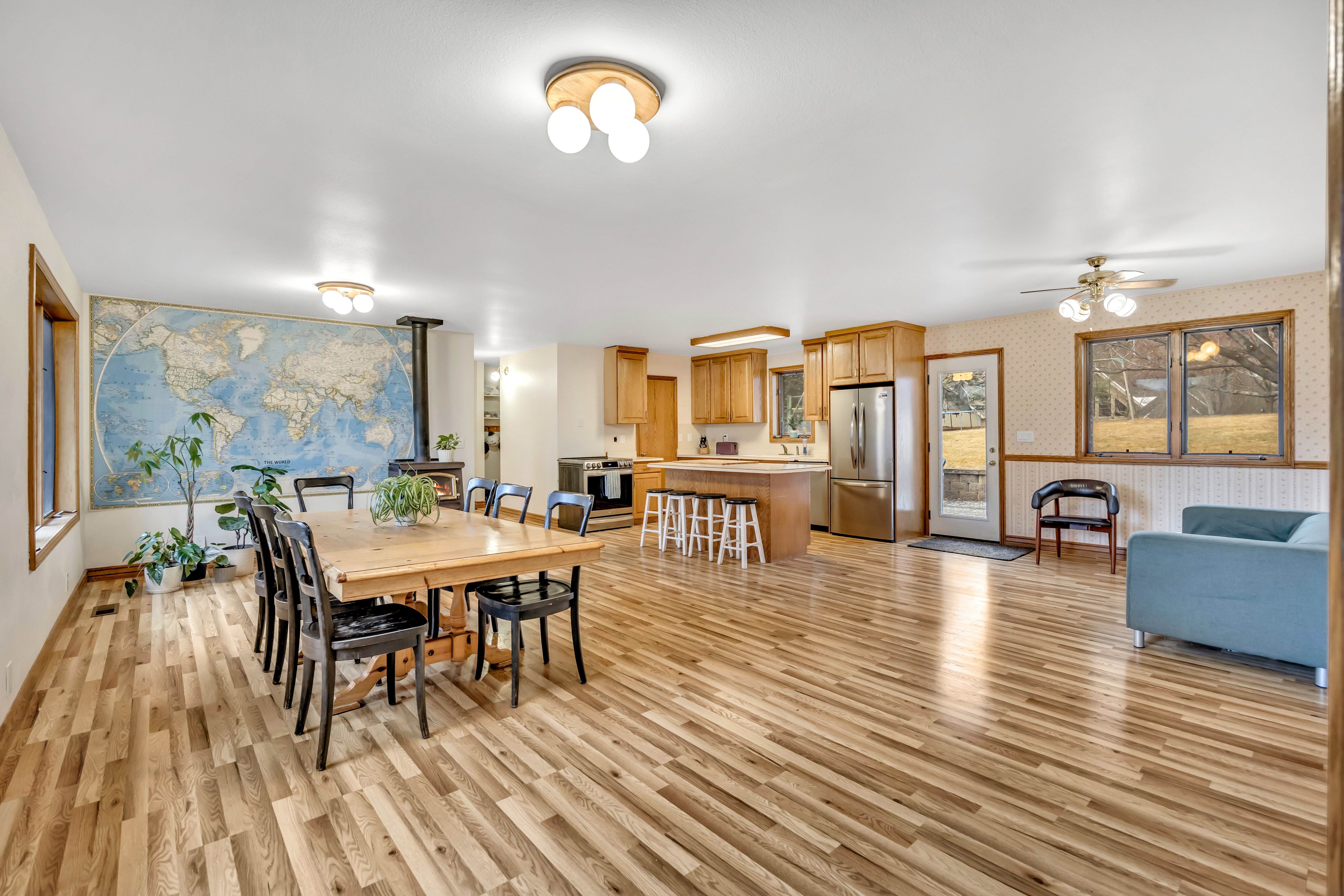 Dining room featuring wallpapered walls, a wood stove, a ceiling fan, and light wood finished floors