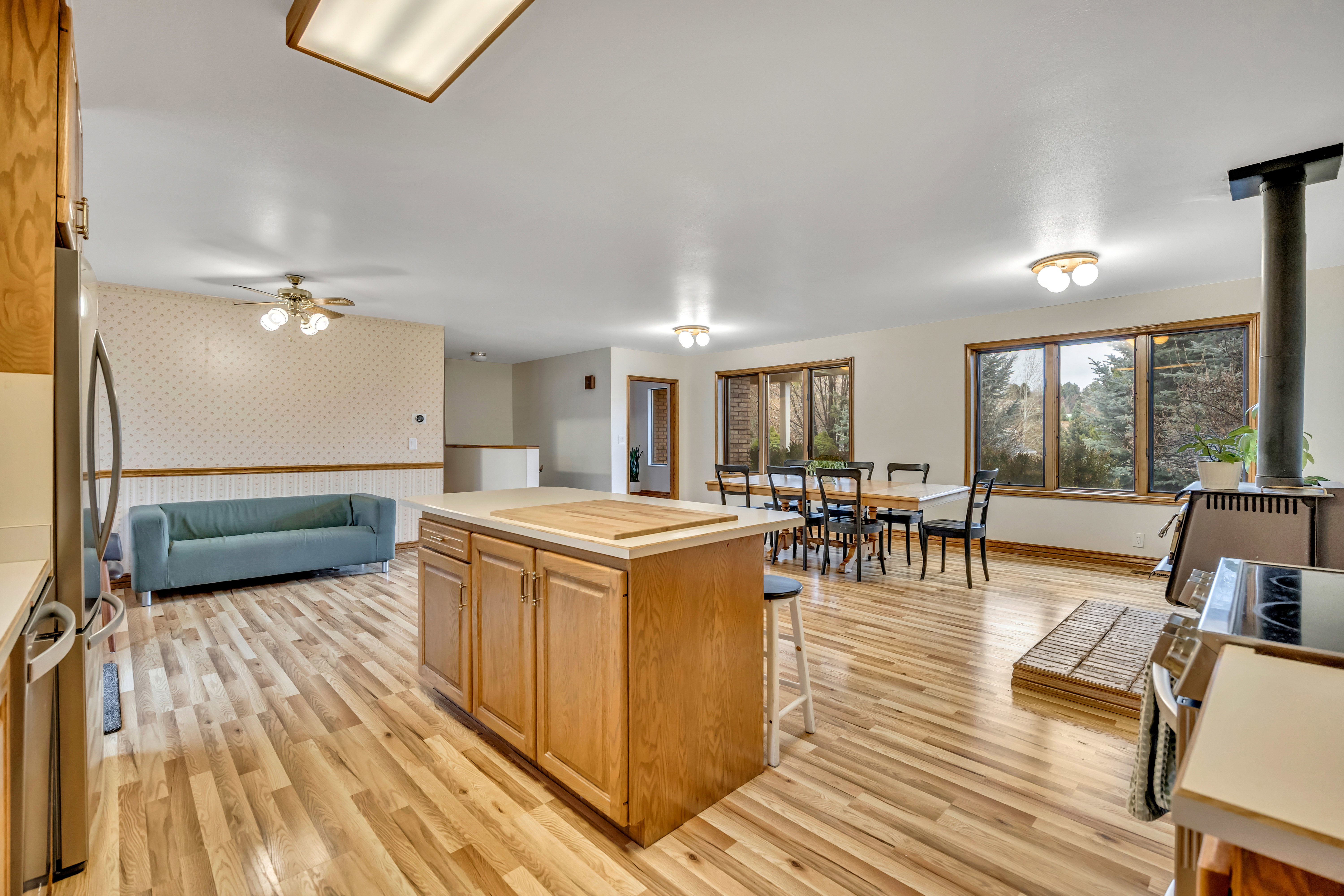 Kitchen featuring wallpapered walls, light wood finished floors, a breakfast bar, a kitchen island, and wood finish cabinets