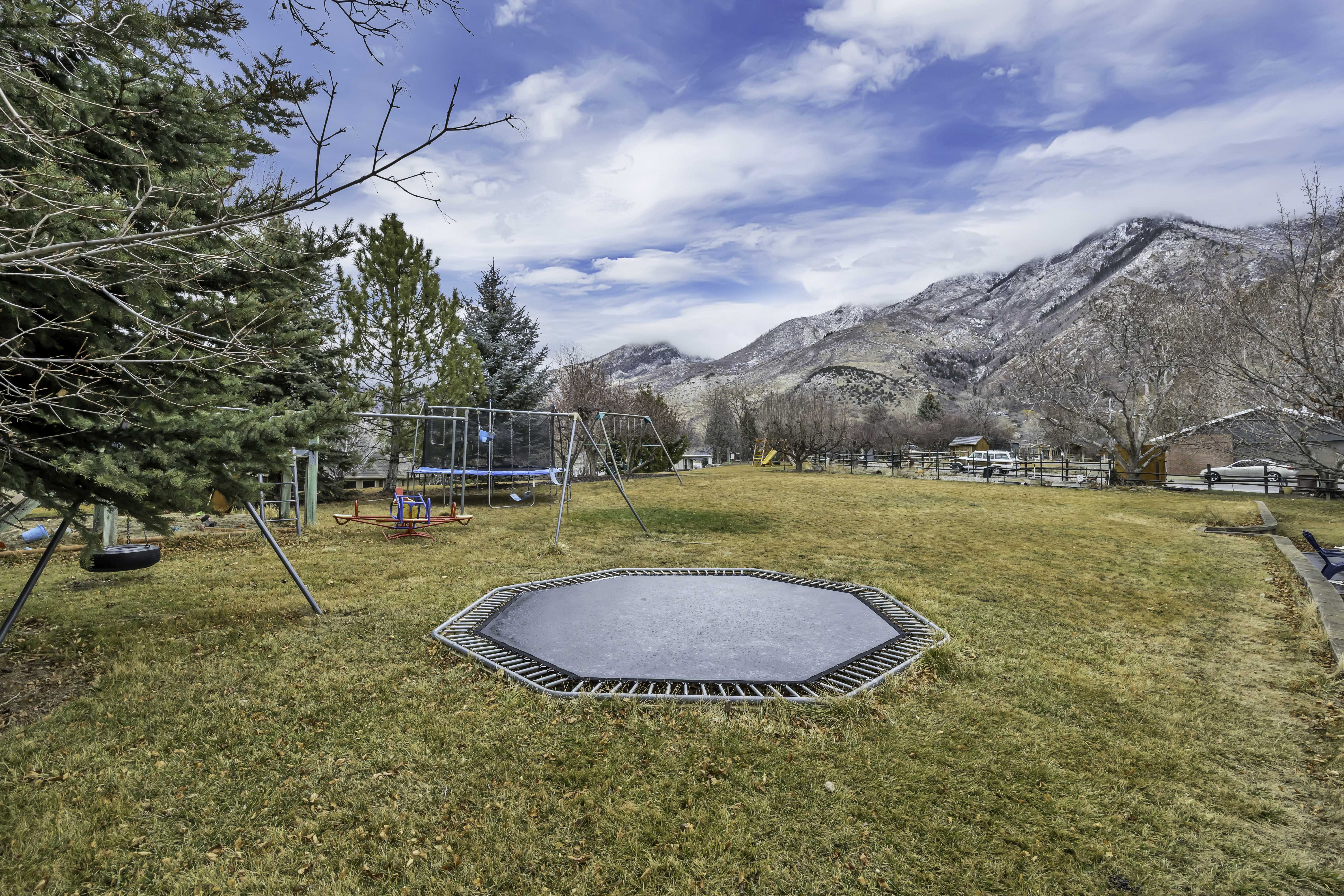 View of green lawn featuring a trampoline and a mountain view