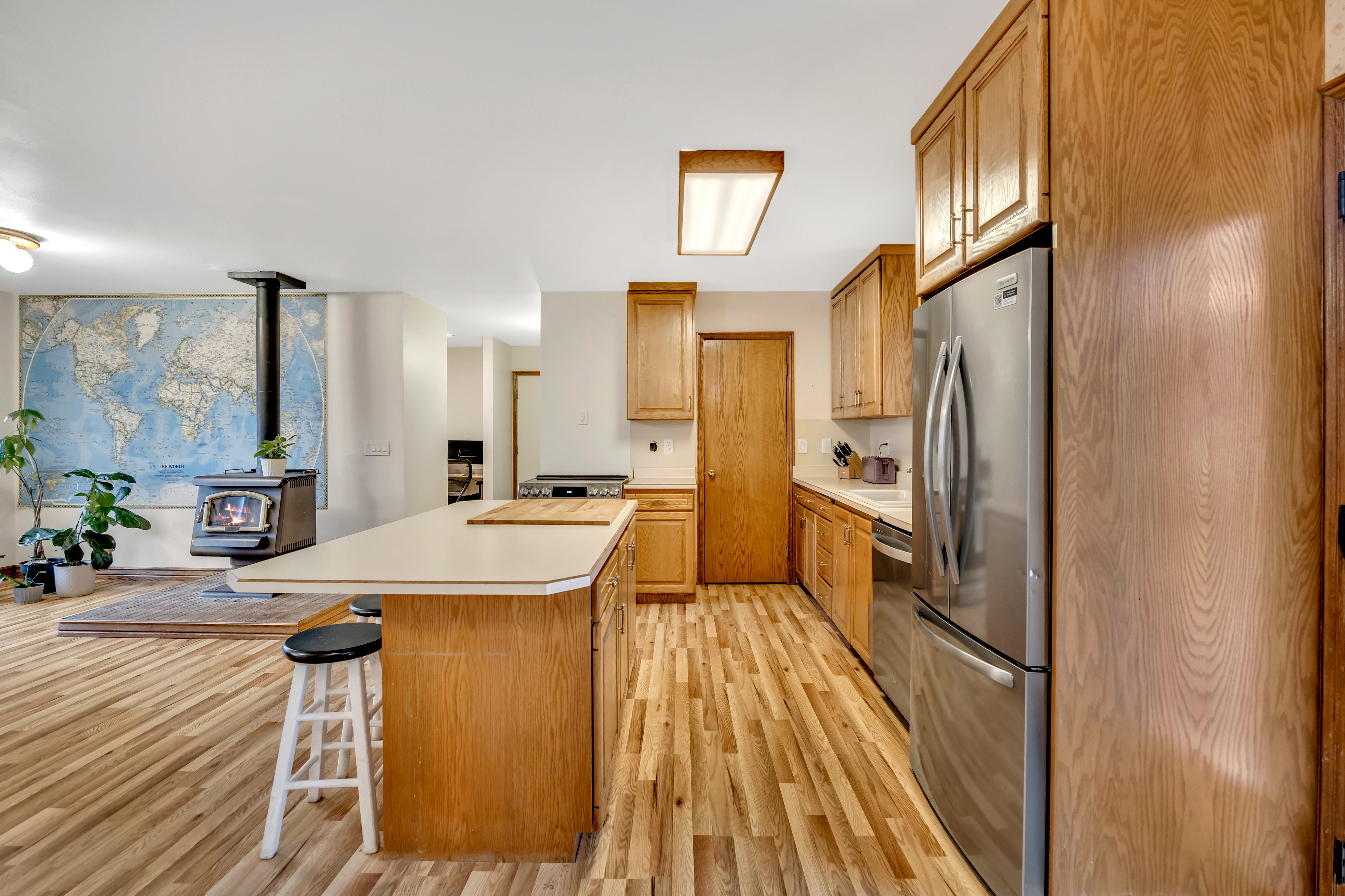 Kitchen featuring light countertops, stainless steel appliances, a breakfast bar area, light wood-style floors, and a wood stove
