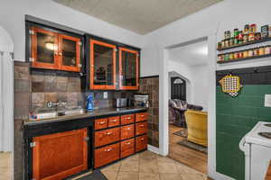 Kitchen featuring tile walls, dark countertops, arched walkways, white range with electric stovetop, and light tile patterned floors