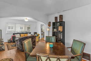 Dining room featuring arched walkways, wood-type flooring, and a desk