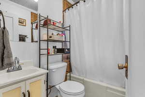 Full bath featuring vanity, shower / bath combo with shower curtain, and ornamental molding
