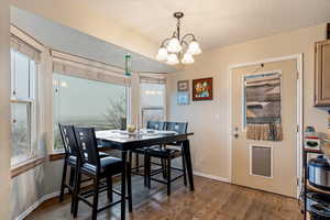 Dining area with hanging lights, light wood-style floors, and a textured ceiling