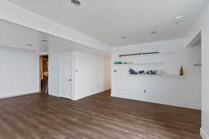 Unfurnished living room featuring dark wood-style floors and baseboards