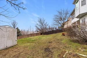 Fenced backyard featuring a storage shed