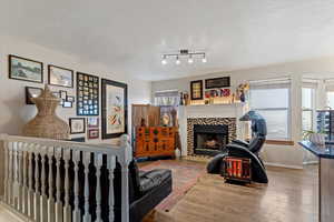 Living area with light wood-style flooring, a textured ceiling, and a tile fireplace