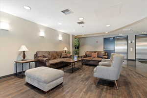 Living room featuring elevator, recessed lighting, and dark wood-style floors