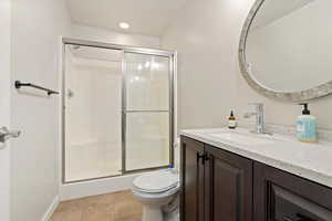 Full bathroom with vanity, a stall shower, light tile patterned floors, and recessed lighting