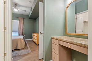 Bathroom with vanity, connected bathroom, ceiling fan, and light wood-type flooring