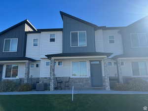 View of front of house with stone siding, board and batten siding, and a front yard