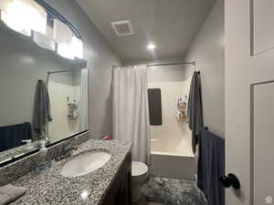 Full bathroom with vanity, shower / tub combo with curtain, and recessed lighting