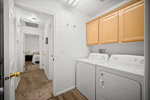 Laundry room with separate washer and dryer, cabinet space, and light wood-style flooring