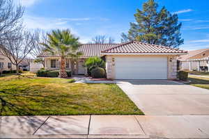 View of front facade featuring a tile roof, a front yard, covered porch, concrete driveway, and stucco siding