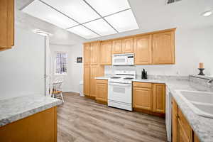 Kitchen with white appliances, light countertops, light wood finish cabinets, and light wood-style flooring