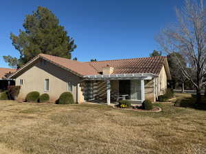Back of property with a yard, a tile roof, and a chimney