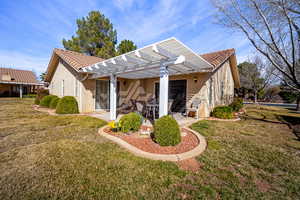Rear view of house featuring stucco siding, a pergola, a yard, a patio area, and a tile roof