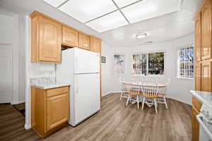 Kitchen featuring white appliances, light countertops, light wood-style flooring, and light wood finish cabinets