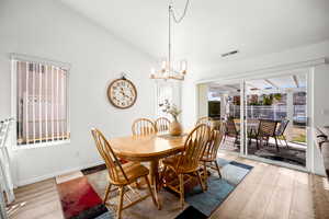 Dining space with light wood-type flooring, hanging lights, and vaulted ceiling