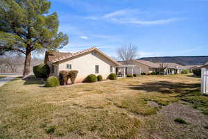 View of side of property with stucco siding, a yard, and a tile roof