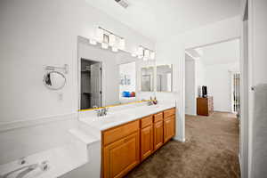 Bathroom featuring double vanity and dark carpet