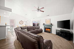 Living area with a ceiling fan, a glass covered fireplace, and a chandelier
