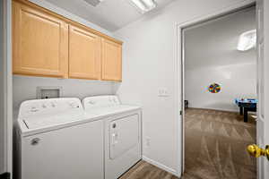 Laundry area with cabinet space, washer and clothes dryer, and light wood-style floors
