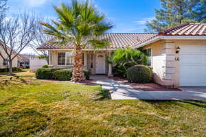 View of front facade with a front lawn, stucco siding, and a tile roof