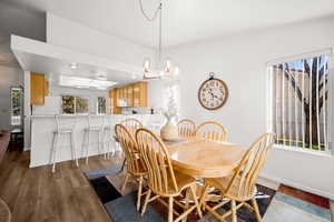 Dining room with dark wood-style flooring and suspended lighting