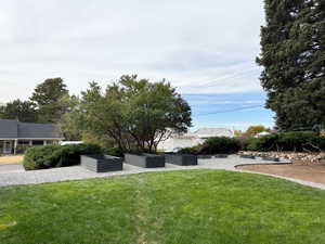 View of grassy yard with a vegetable garden and a patio area, from summer time