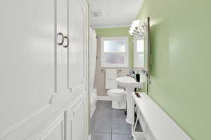 Full bath with a textured ceiling, crown molding, dark tile patterned flooring, tile walls, and shower / tub combo