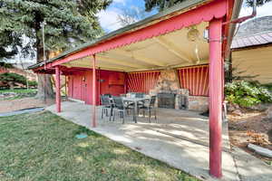 View of patio with outdoor dining area and a stone fireplace