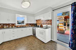 Kitchen featuring dark countertops, white gas range oven, white cabinetry, tasteful backsplash, and stainless steel dishwasher