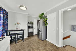 Kitchen with stone finish flooring, stainless steel appliances, crown molding, and electric panel