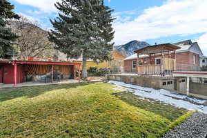 Rear view of house with a patio, a mountain view, and a lawn