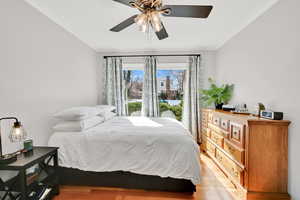 Bedroom featuring light wood-style flooring, a ceiling fan, and ornamental molding