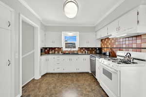 Kitchen with white range with gas cooktop, dark countertops, white cabinetry, stone finish flooring, and decorative backsplash