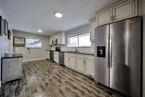 Kitchen featuring stainless steel appliances, dark countertops, dark wood-style flooring, tasteful backsplash, and a textured ceiling