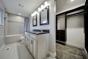 Full bathroom with double vanity, tiled shower / bath combo, recessed lighting, light colored carpet, and light tile patterned flooring