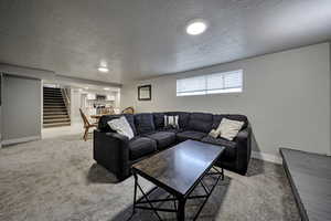 Living area with a textured ceiling, light colored carpet, and recessed lighting