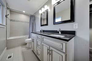 Full bathroom featuring double vanity, tiled shower / bath combo, light tile patterned flooring, and recessed lighting