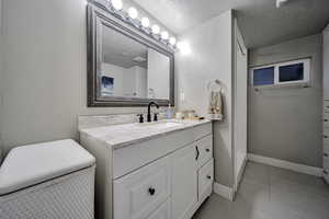 Bathroom featuring vanity, a walk in shower, light tile patterned floors, and a textured ceiling